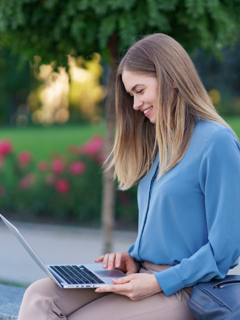 Young women working on laptop in the city square